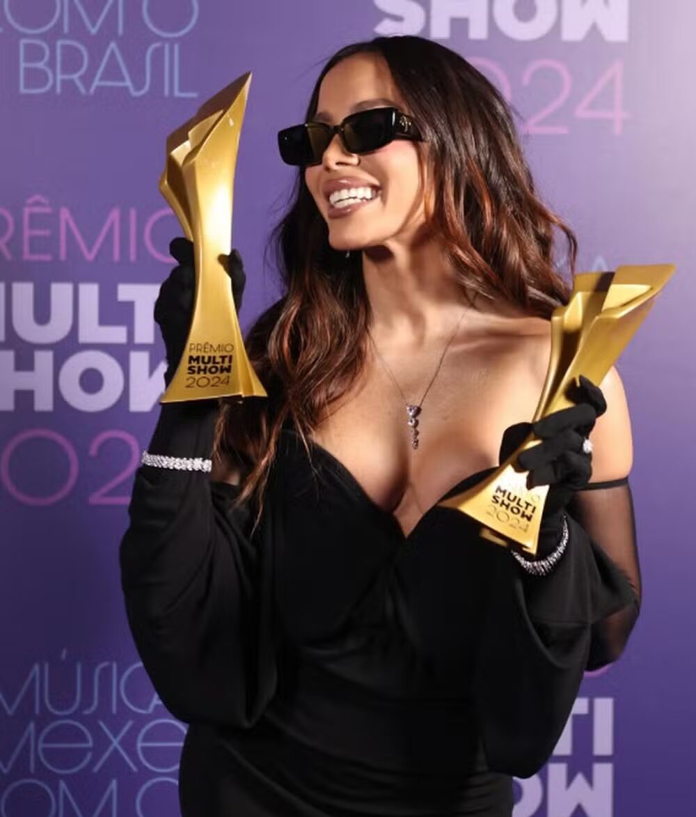 Cantora Anitta segurando 2 troféus do Prêmio Multishow 2024.